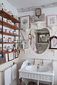 Chinaware collection on wooden bathroom shelves with mirror above sink in Dorset home  Kent  UK