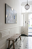 Modern art canvas above wooden bench in tiled entrance hallway of South Kensington townhouse  London  UK