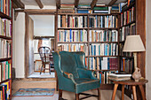Blaugrüner Ledersessel und Beistelltisch mit Bücherregalen in einem Bauernhaus in Ashford, Kent, Großbritannien