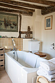 White bathtub with shower fitting and ornaments in timber framed Ashford farmhouse  Kent  UK