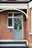 Weihnachtskranz an der Eingangstür eines Londoner Hauses mit gefliester Türschwelle England UK