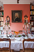 Dining table with bookshelf and glass candelabras in London home  England  UK