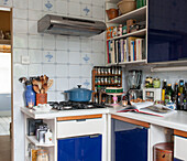 Wooden spoons and spice rack with casserole on hob in blue fitted London kitchen  England  UK