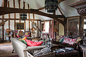 Log basket and sofas in timber farmed living room of Suffolk home  England  UK