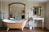 Freistehende Badewanne und großer Spiegel mit Waschtisch im Badezimmer in Suffolk England UK