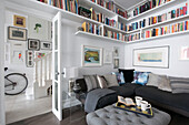 Book shelving above corner sofa with view through doorway in South London Victorian terraced house