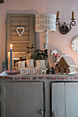 Lamp and lit candle with gingerbread house on grey cupboard in Grade II listed cottage  Kent