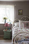 Floral quilt on bed at window with net curtains in Grade II listed cottage  Kent