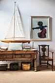 Model boat on antique table with chair and artwork in Norfolk coastguards cottage  England  UK