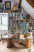 Vintage chair and table with bookcase at window in Norfolk coastguards cottage  England  UK