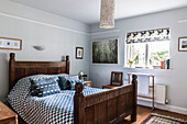 Blue checked cover on antique wooden bed in Norfolk coastguards cottage  England  UK