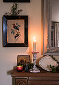 Framed artwork and lit candle on wooden mantlepiece in East Sussex coach house  England  UK