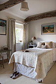 Single bed with cream quilt at window in East Sussex coach house  England  UK