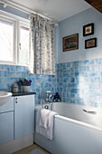 Blau gefliestes Badezimmer unter dem Fenster in einem Kutschenhaus in East Sussex, England, Vereinigtes Königreich