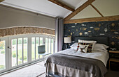 Double bed and chair at window in Oxfordshire barn conversion  England  UK