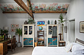 Zimmerpflanzen und Wanddekoration mit Schränken und Schreibtisch im Schlafzimmer einer umgebauten Scheune in Oxfordshire, England UK