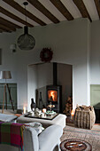 Teatray on ottoman with lit woodburner in sitting room of Grade II Listed priory  Headcorn  Kent  UK