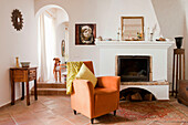 Dog in arched doorway of split level terracotta tiled living room with orange armchair at fireside Castro Marim Portugal