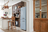 Light blue upright fridge and wooden glass fronted cabinet in Brighton kitchen with exposed brickwork, East Sussex, England, UK