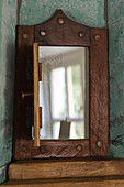 Wooden mirror with rivets and hinged door in Devon cottage England UK