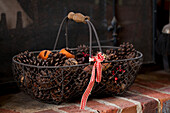 Pine cones in wire basket with ribbon on Amberley fireplace West Sussex UK