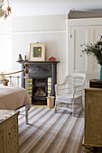 Wicker chair at fireside with striped rug in Edwardian West Sussex townhouse England UK