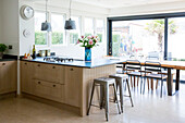 Cut flowers on workbench in open plan kitchen with table and chairs West Wittering home West Sussex England