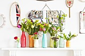 Cut tulips in vases on mantlepiece with mirror display in London family home,  England,  UK