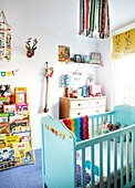 Book storage in child's nursery with turquoise painted cot,  London family home,  England,  UK