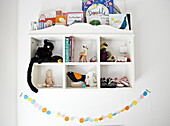Soft toys and books on wall-mounted shelving in London family home  England  UK