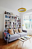 Großes Bücherregal und Sofa im Wohnzimmer mit Parkettboden in einem Einfamilienhaus in London England UK