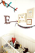 Artwork and mobile with letter 'E' above child's cot in London family home  England  UK