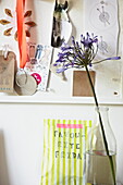 Noticeboard and single stem flower in milk bottle  London family home  England  UK