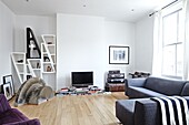 Shelving unit and grey sofa in living room of contemporary London family home   England   UK