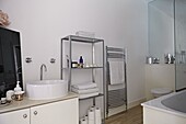 Silver metallic shelving and wall mounted radiator in contemporary London family home   England   UK