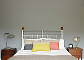 Pastel pillows on double bed with vintage bedside cabinets in contemporary London home   England   UK