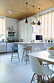 Spacious open plan kitchen with stools at breakfast bar,   London family home,  England,  UK