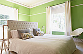 Buttoned headboard on double bed in bright green London bedroom  England  UK