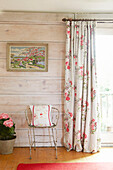 Old metal chair with cushion at French doors with artwork in UK farmhouse