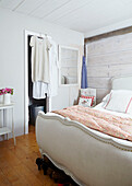 Weißes gepolstertes Fußteil in einem getäfelten Schlafzimmer in einem britischen Bauernhaus