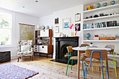 Retro styled sideboard with black fireplace and shelving in living room of London family home,  England,  UK