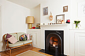 Victorian fireplace with wooden sofa in living room of Faversham home,  Kent,  UK