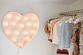 Beaded tops on clothes rail with heart shaped light in Faversham work studio,  Kent,  UK