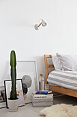 cactus and magazines with framed artwork at bedside in London apartment  UK