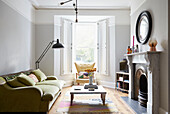 Circular mirror above marble fireplace with vintage sofa in London home  UK