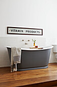 Schild 'Vitaminprodukte' über einer modernen grauen freistehenden Badewanne in einem Londoner Haus UK