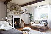 Lit fire in exposed stone chimney breast with seating in West Yorkshire living room  UK