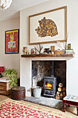 Ornamente auf dem Kaminsims über dem beleuchteten Holzofen im Wohnzimmer von Berwick Upon Tweed in Northumberland UK