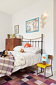 Kuscheltiere auf einem Bett mit Metallrahmen und kariertem Teppich in einem Haus in Berwick Upon Tweed, Northumberland UK