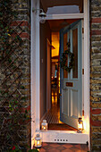 Lit lanterns and open doorway with view into London home  UK